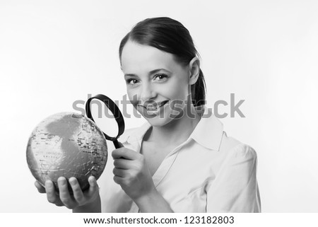 woman holding up a jigsaw globe puzzle and looking at it with a inspecting eye with a magnifying glass