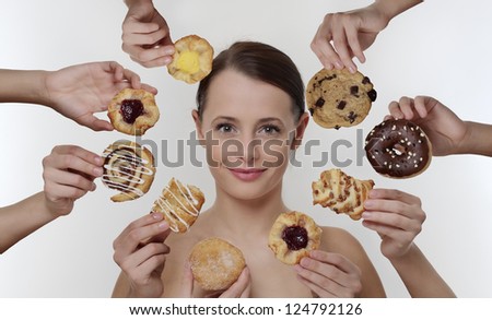 woman surrounded by many hands holding cream cakes with so much choice and temptation is she going to forget about her diet and indulge herself