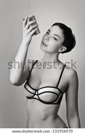 fashion style image of sexy woman in underwear taking singing into a tin can on string