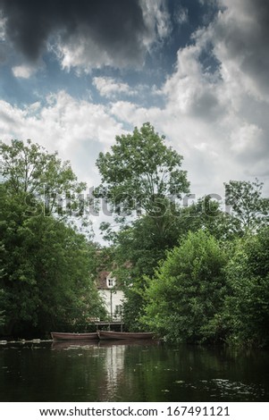 View of house next to river hidden by trees and bushes, England