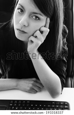 office worker sitting at her desk deep in thought but looking unhappy about something