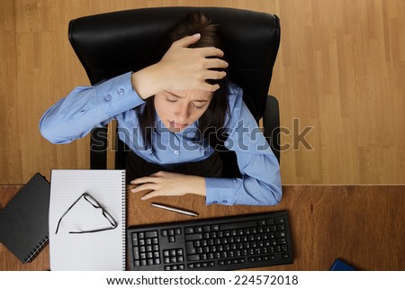 woman at her desk feeling the stress of work, taken from a birds eye view