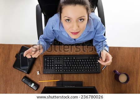 Woman sitting at her desk looking. Image is shot from a birds eye view looking down.