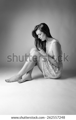 black and white image of woman shot in the studio sitting on the floor wearing a lace dress