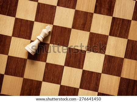 background image of a wooden chess board with just the white king on it\'s side as if he has lost the game