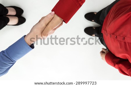 shot from above of two female business women shaking hands as they meet