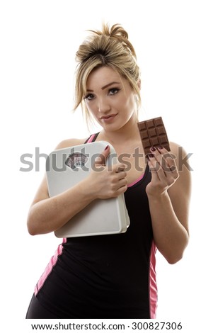 fitness woman holding scale and a bar of chocolate not sure if she should eat it