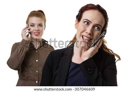 two woman on a mobile phone one stand in front as the main focal point