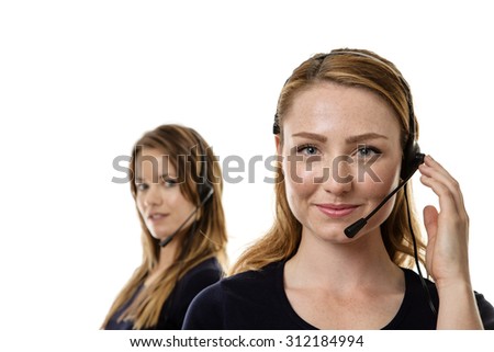 two woman one standing in front in focus wearing a head set talking
