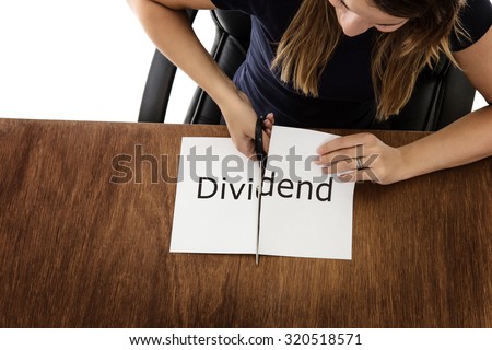 woman shot from above cutting paper in half with the word dividend written on