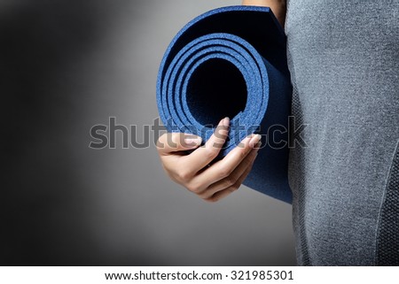 close up shot of woman holding a yoga mat up to her midmidriff