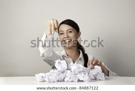 young woman throwing paper ball at someone or something having fun at her work desk