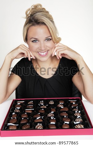 woman with a large box of chocolate and she just eaten one she does not like