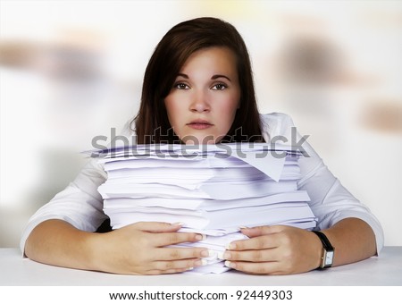 woman at desk looking and thinking about all the paper work she needs to do