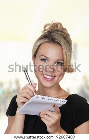 woman shot in the studio on white background holding a pen and note book talking notes