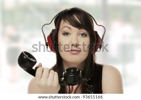 woman on the phone with ear defenders on so she cant hear what the person on the other end of the phone has to say