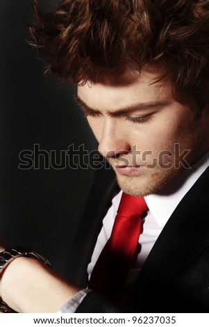 low key image of businessman looking at his wrist watch do you think hes running late