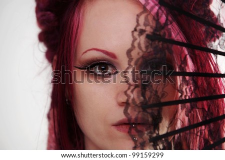 woman with dread lock hair holding a fan up to her face