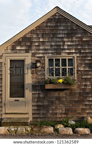 Simple craftsman style cottage with wood shingles and flower-filled window box.