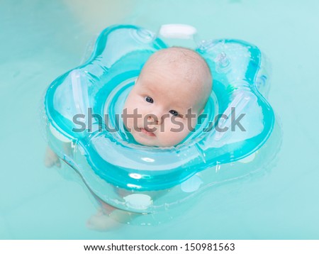 Baby swimming with neck swim ring in pool