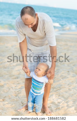 Father is helping his son to make first steps outdoor