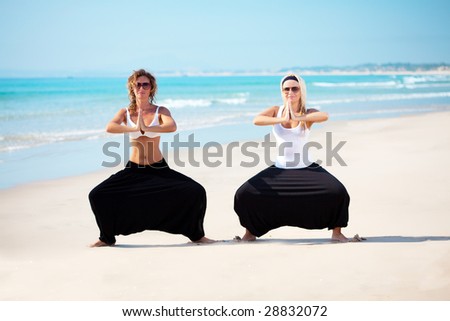 Two young beautiful woman in cambodian pants doing yoga exercises