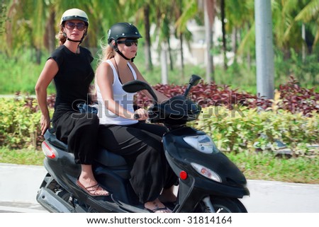 Two tourist woman riding motorbike on road. Vietnam