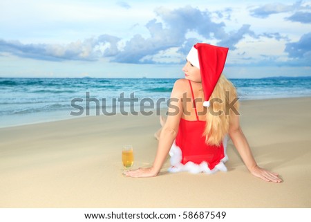 Miss Santa sitting near the ocean with glass of wine