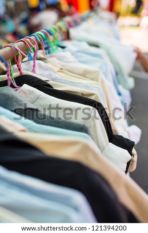 Old shirt hanging on plastic hangers in second hand market