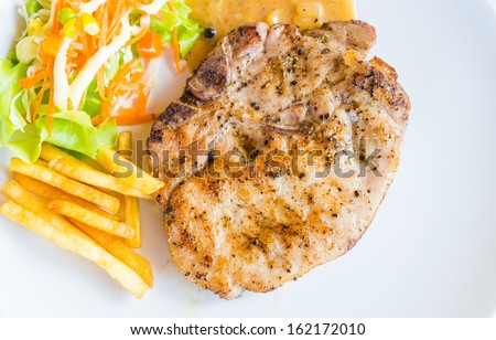 T-bone pork steak on white dish with salad french fries and pepper gravy sauce