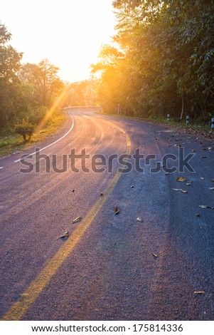 road in the mountain with yellow line and sunrise flare effect