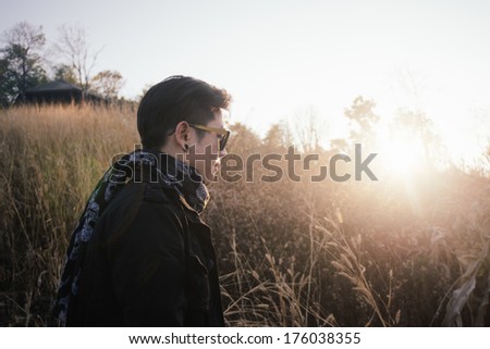 Vintage photo of young man with sunrise in grass field morning time and lens flare effect