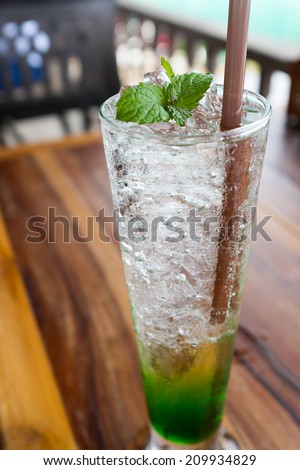 mint soda fresh cold drink soda water ice cubes in glass peppermint on topping on wood table in restaurant