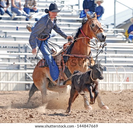 Young cowboy dismounting his horse after roping a calf during a rodeo.