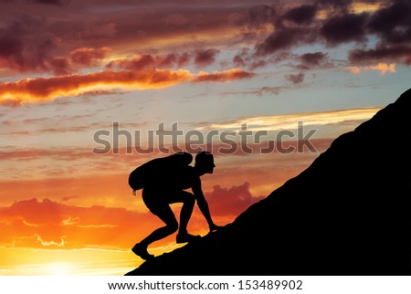 Silhouette of a man that climbs the mountain on sunset sky background. Climbing a mountain.