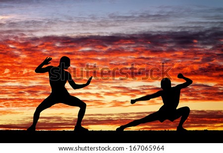 Silhouettes of two fighters on sunset fiery background