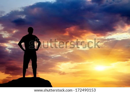 Silhouette of man on rock at sunset. Man on top of mountain. Conceptual design.