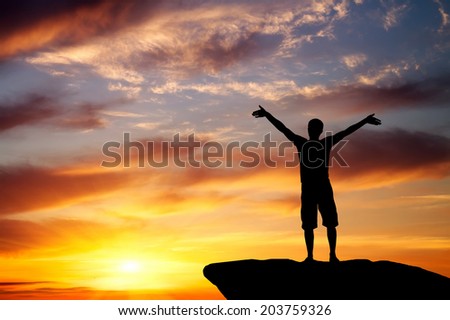 Silhouette of a man on a mountain top on fiery orange background