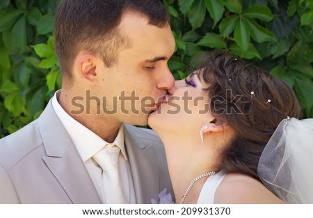 Beautiful newly married couple are kissing in the park