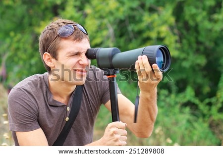 Man who is watching in spotting scope. Positive man looking through a telescope