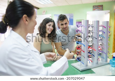 Couple choosing glasses at optical store