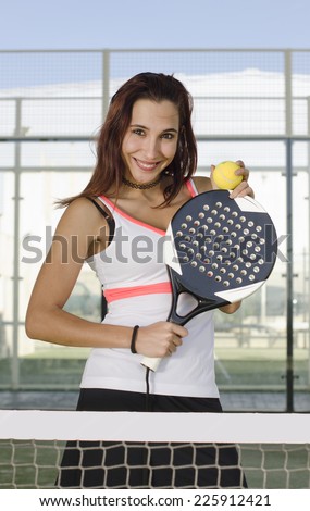 Paddle tennis woman player posing with racket and ball in outdoors court