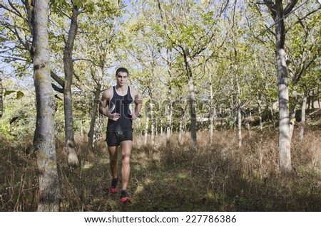 Runner young man in he forest full length portrait