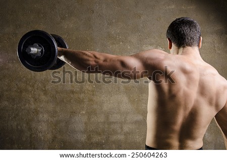 Man lifting weights, back image at old gym.