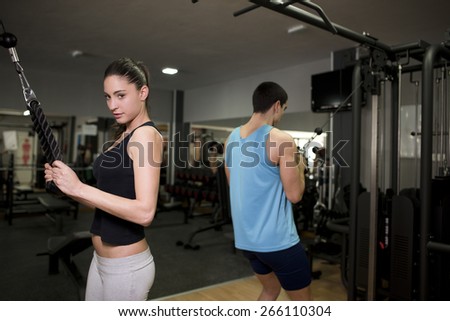 Young couple training at gym with pull triceps exercises