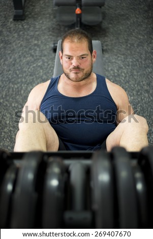 Regular man training legs in press gym machine with ambient light