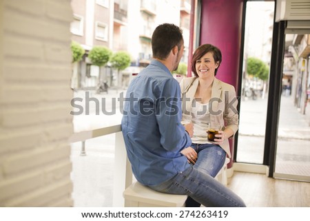 Couple in bar having date, eating and drinking with ambient window lights
