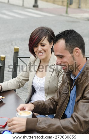 couple touching smartphone and drinking coffee in restaurant terrace