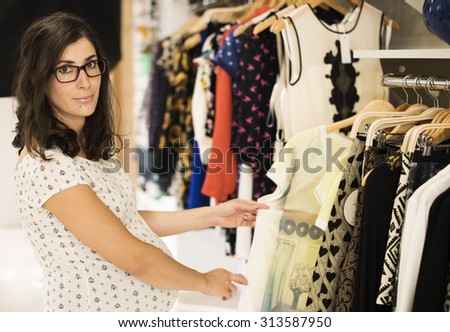 Pregnant woman in clothes store looking some clothes to buy