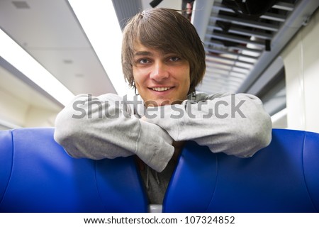 Young, handsome man, looking back over the benches in a train compartiment